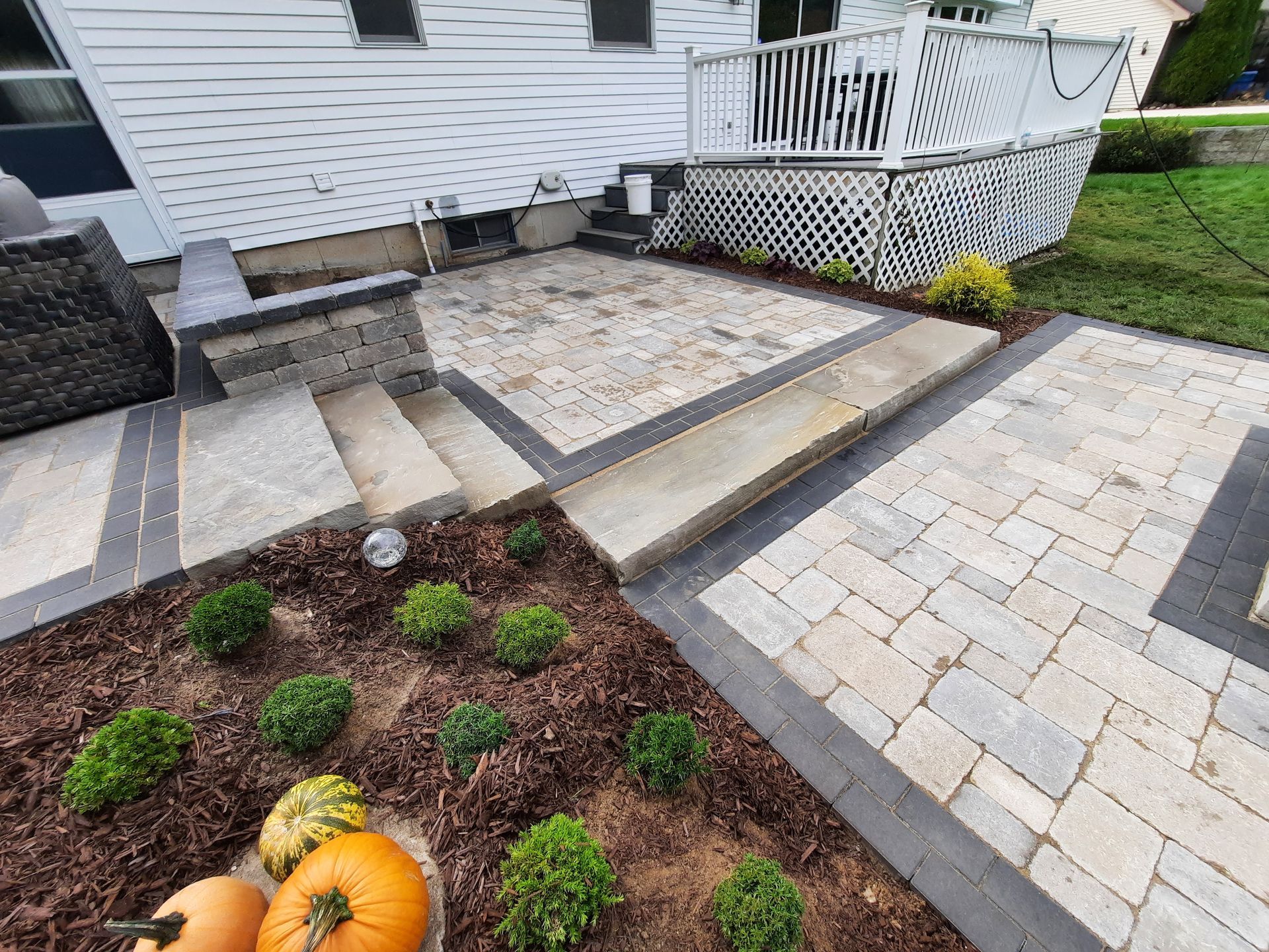 A patio with stairs and pumpkins in front of a house.