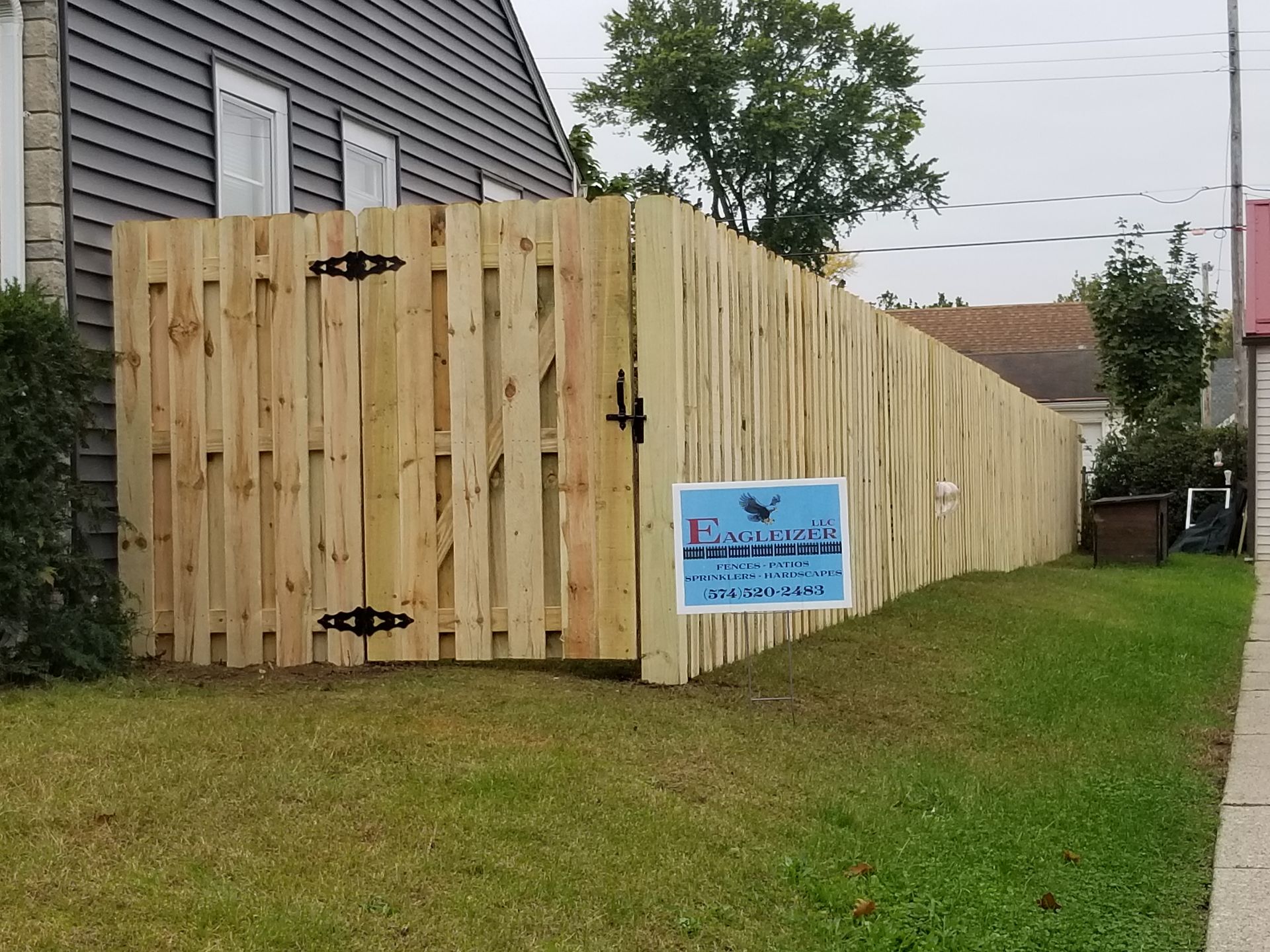A wooden fence with a gate is in front of a house.