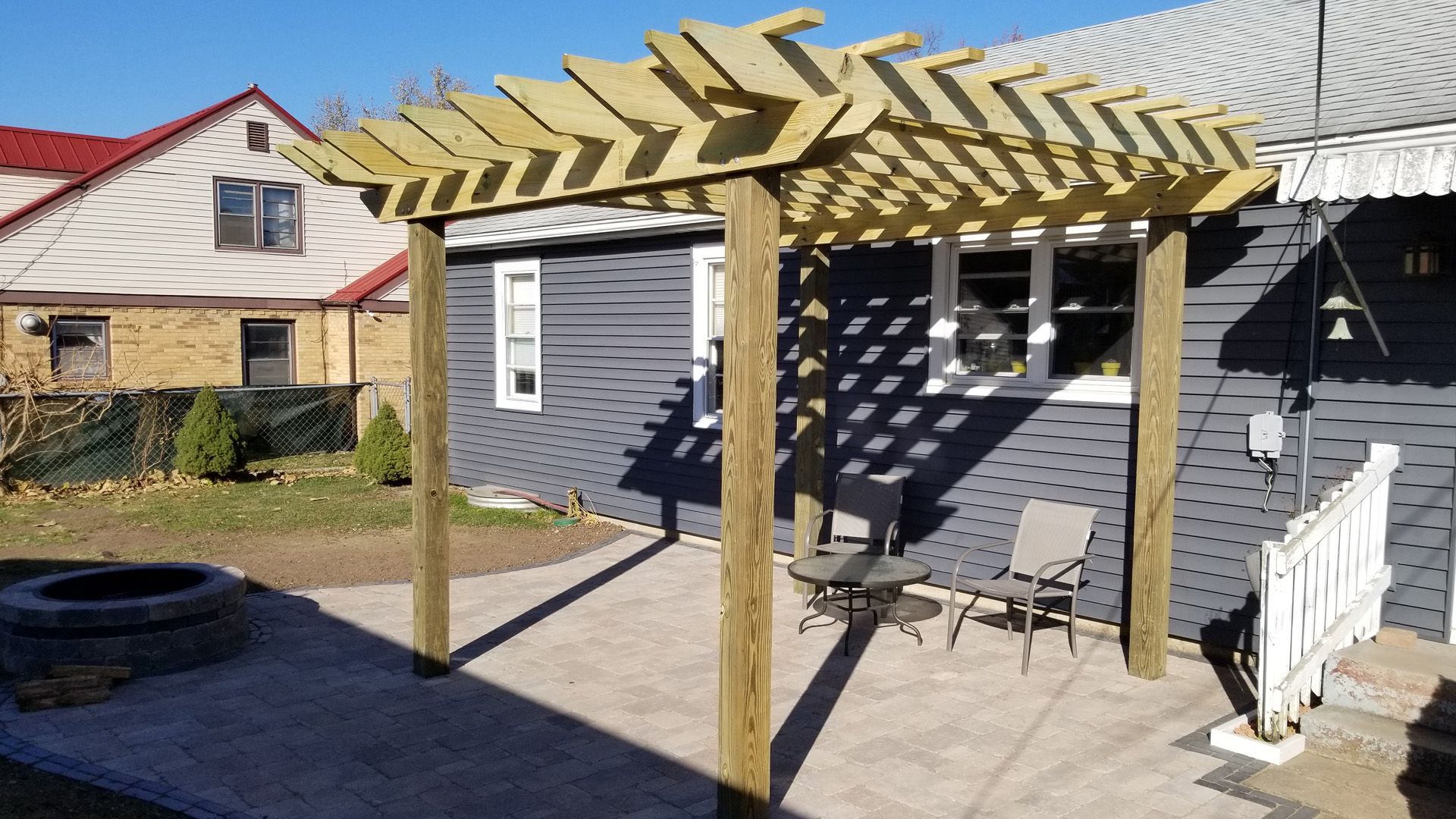 A wooden pergola is in the backyard of a house