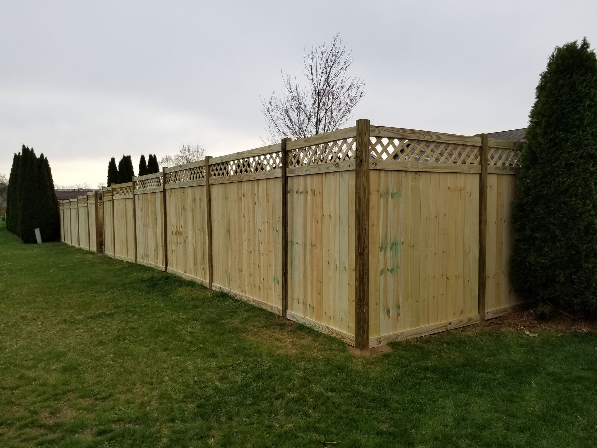 A wooden fence is sitting in the middle of a lush green field.