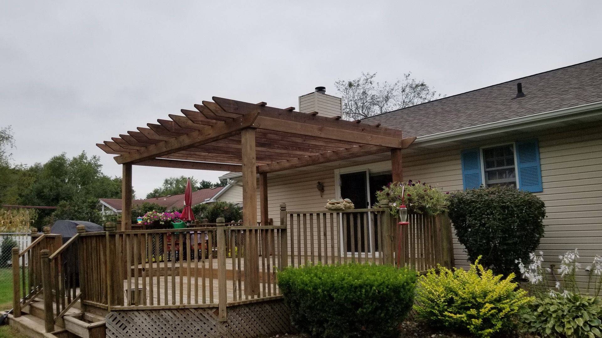 A house with a wooden deck and pergola in front of it.