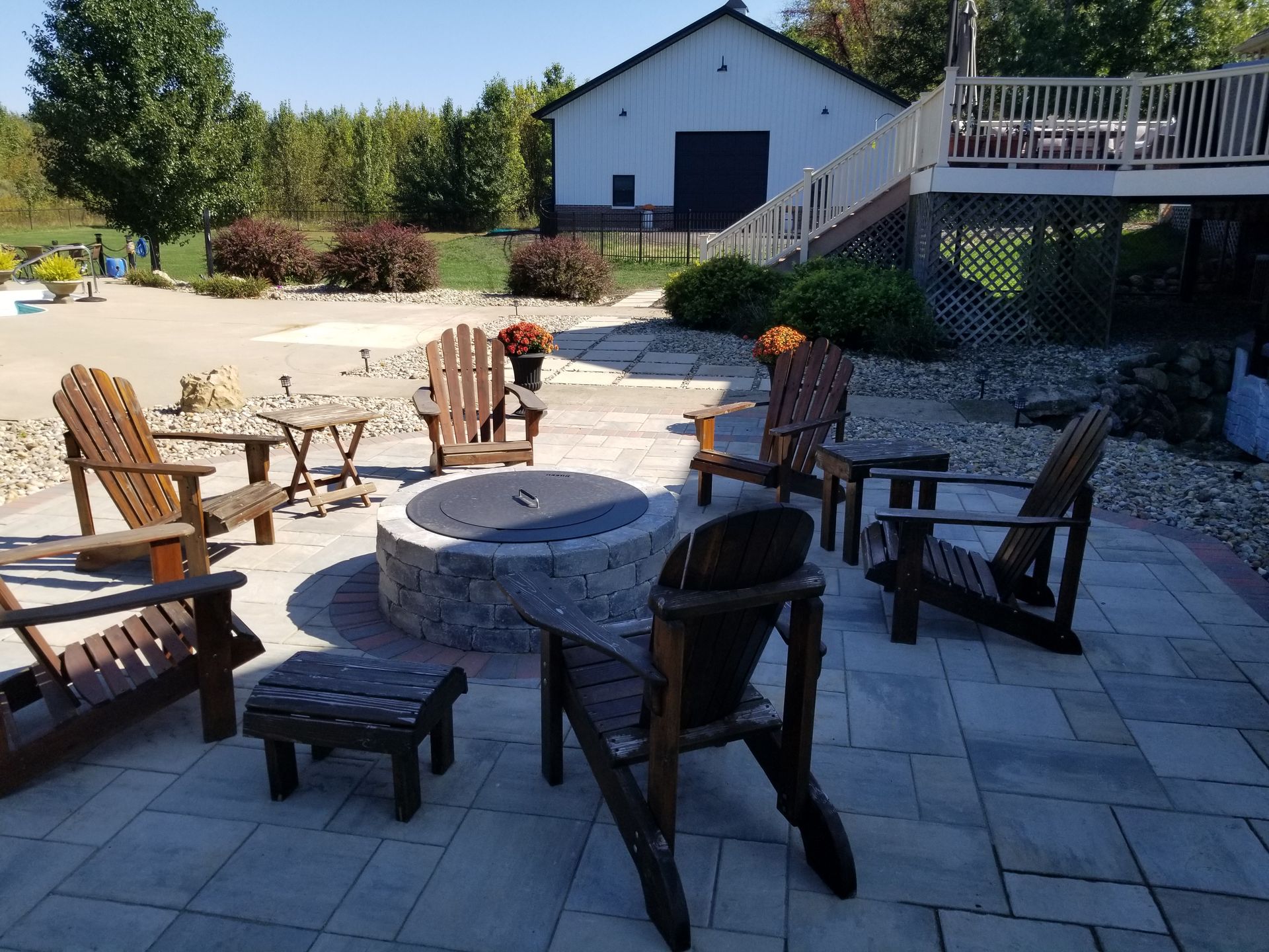 A fire pit is surrounded by chairs and tables on a patio.