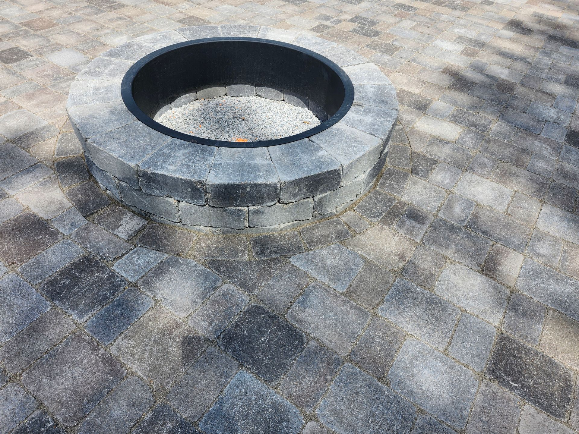 A fire pit is sitting on top of a brick patio.