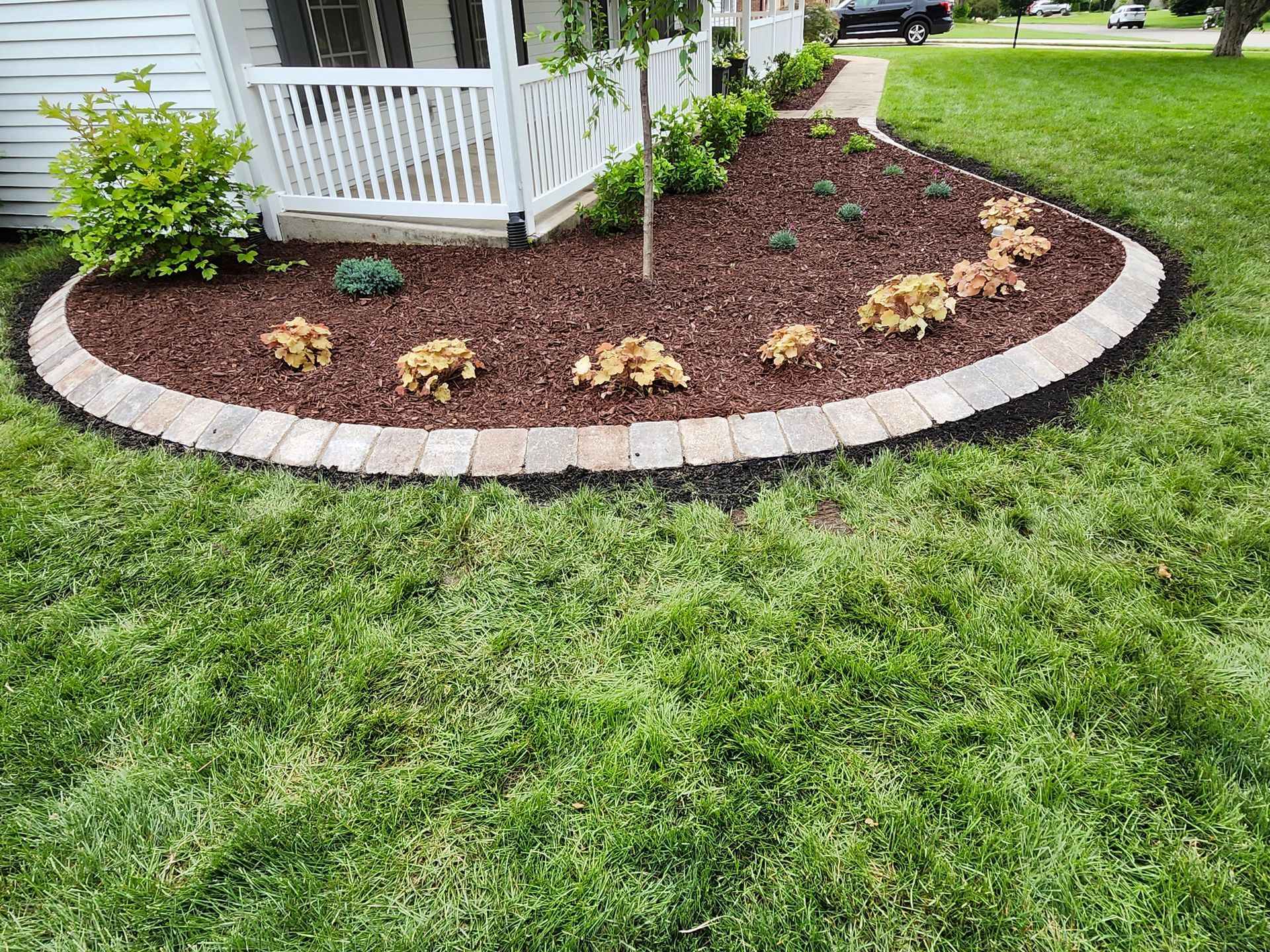 A lush green lawn with a circular garden in front of a house.