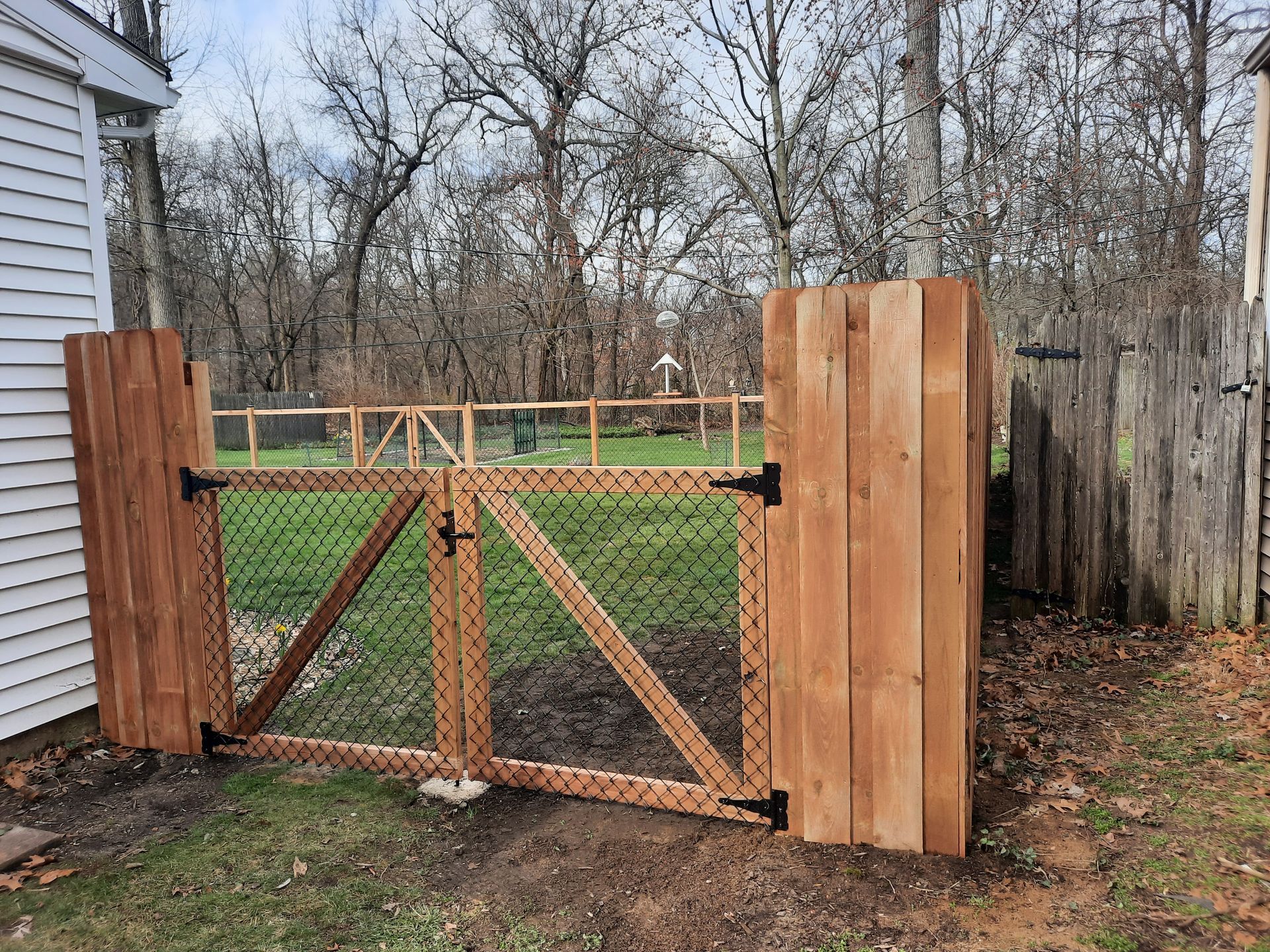A wooden gate is sitting next to a chain link fence.