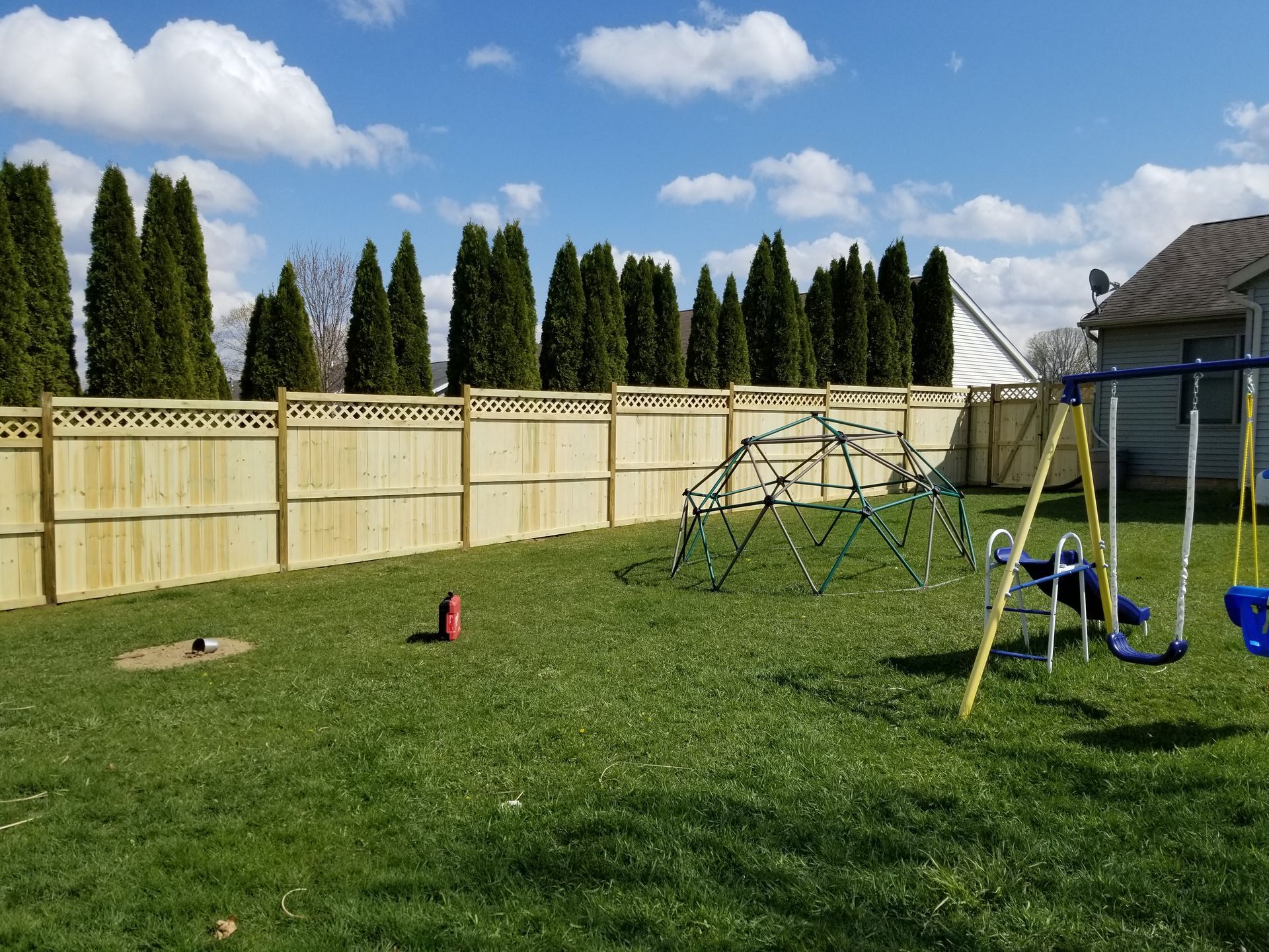 A backyard with a wooden fence and a swing set.