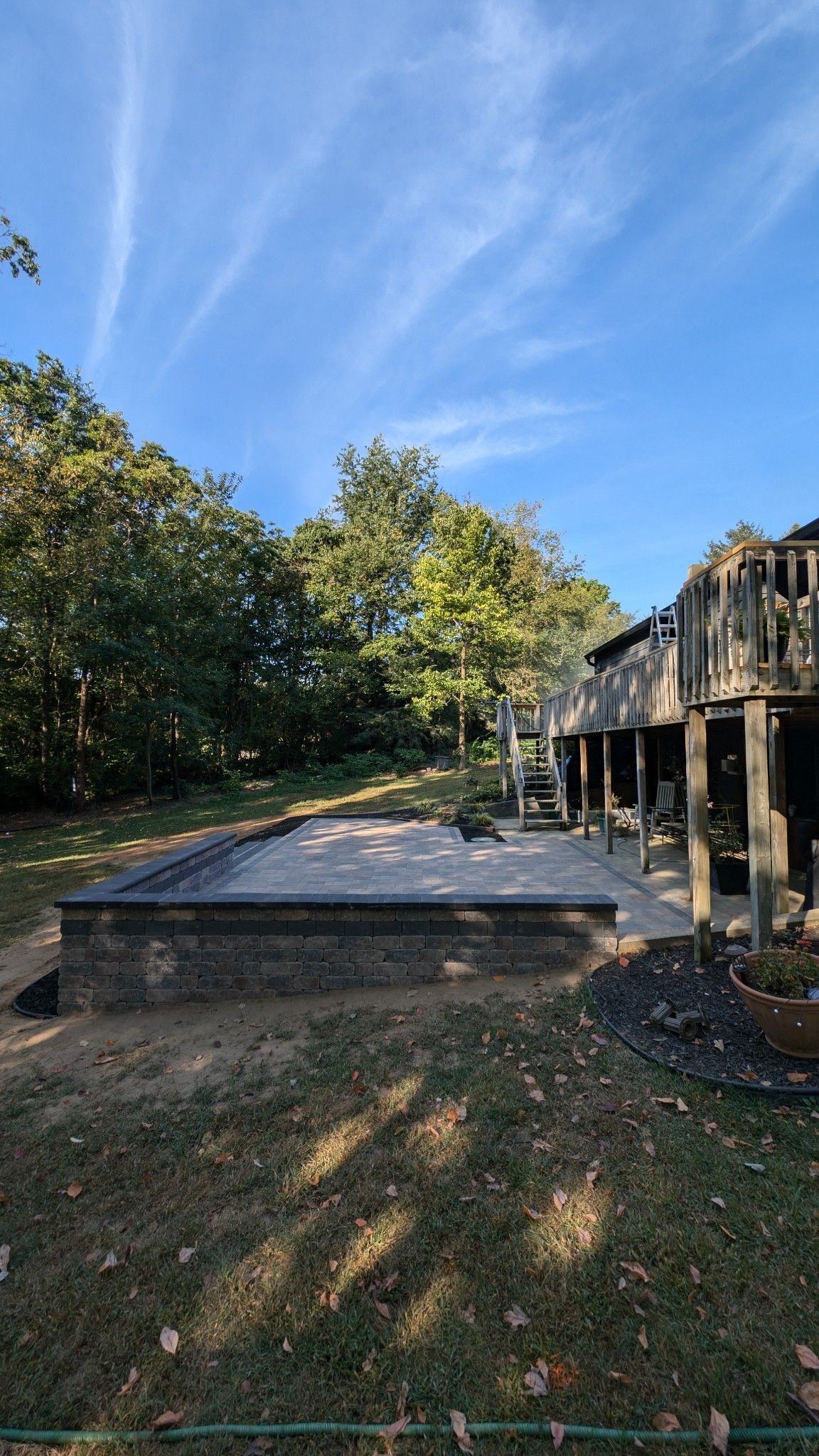 A backyard with a large deck and a sandbox in the middle of it.