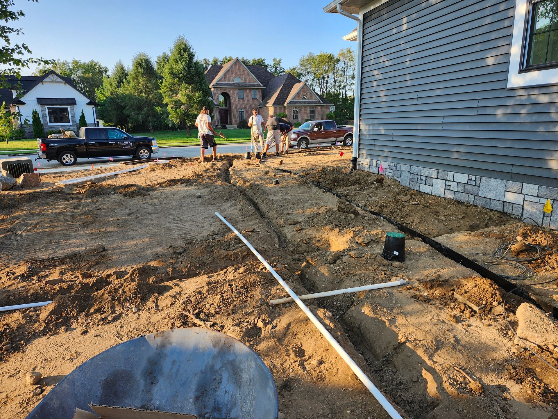 A group of people are standing in the dirt in front of a house.