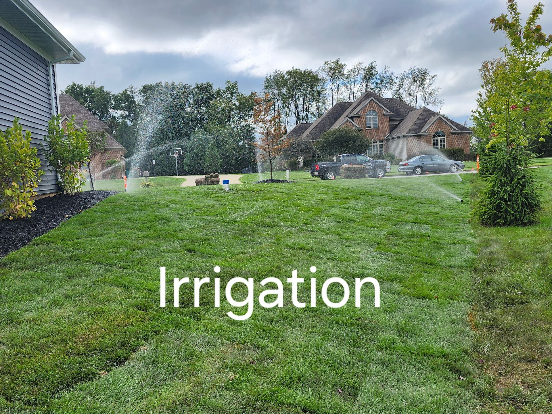 A sprinkler is spraying water on a lush green lawn in front of a house.