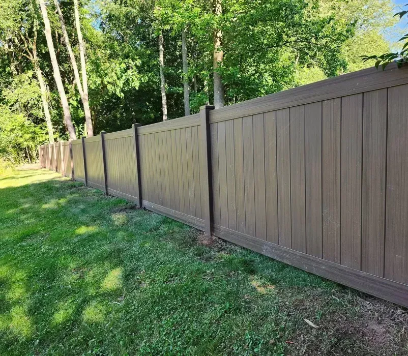 A brown wooden fence surrounds a lush green yard.
