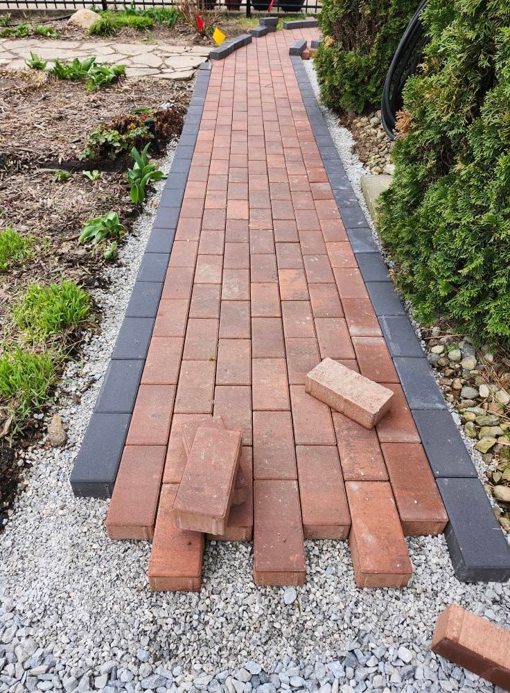 A brick walkway is being built in a garden