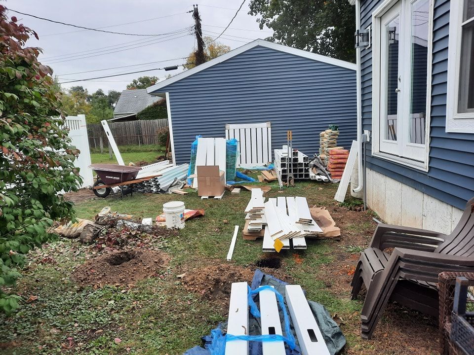 A backyard filled with lots of junk and a house in the background.