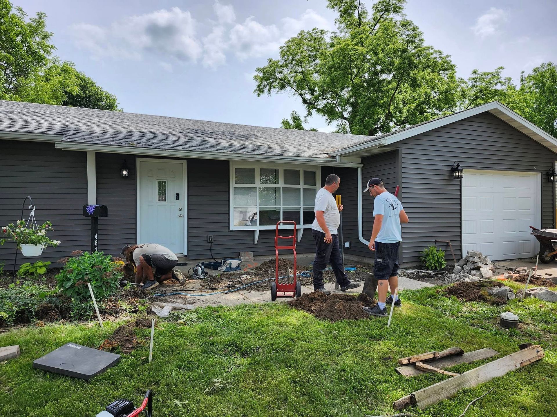 Two men are digging in front of a house.