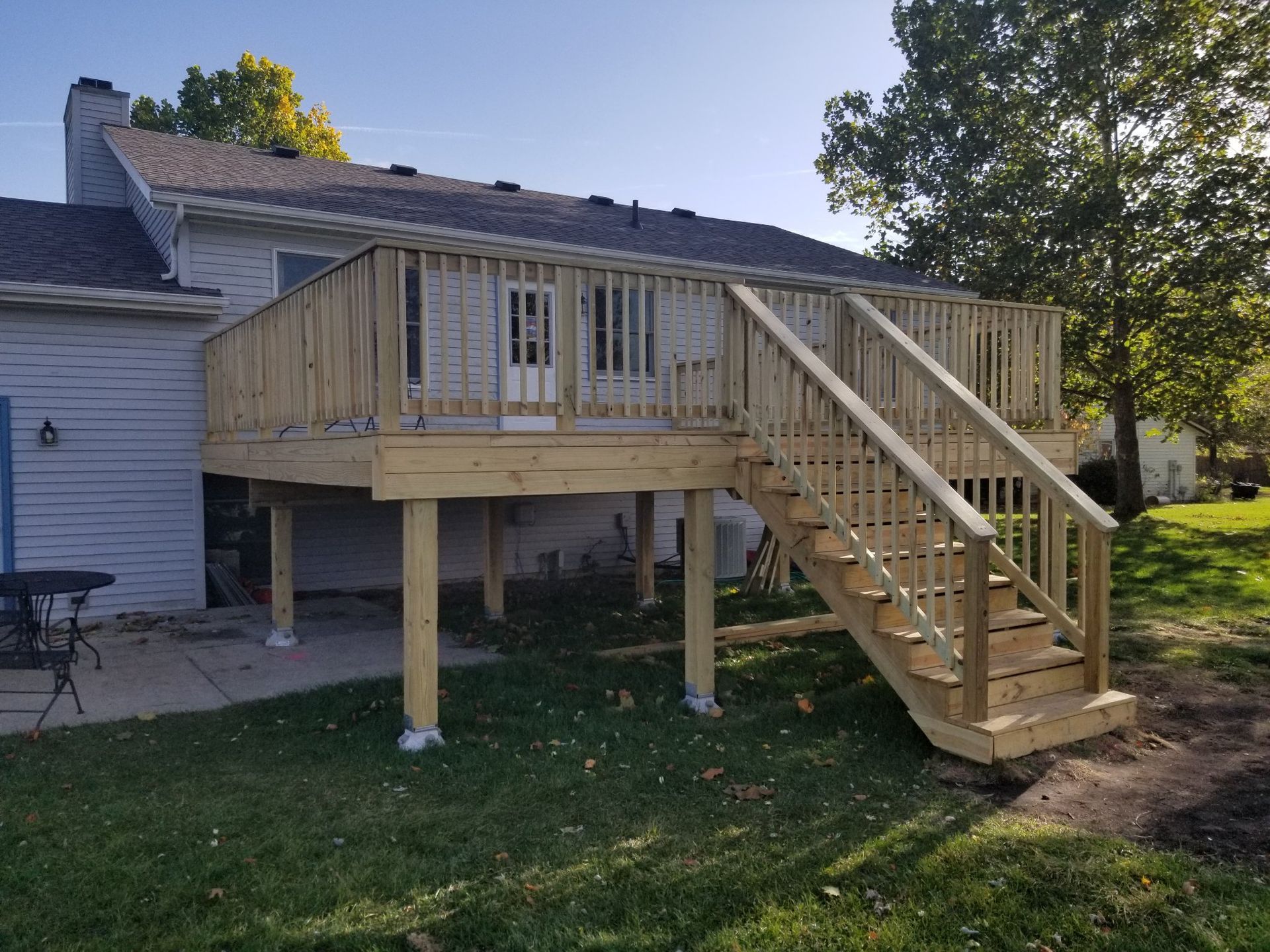 A wooden deck with stairs leading up to it is in front of a house.
