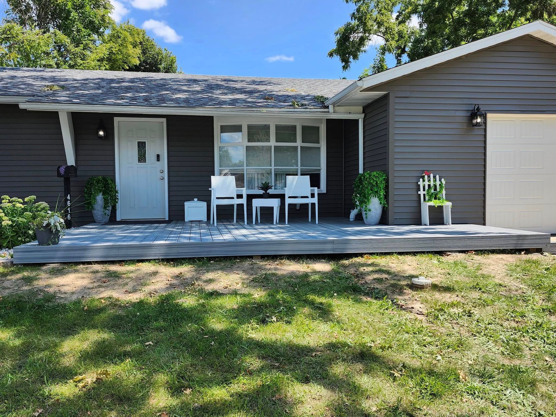A house with a porch and chairs in front of it.