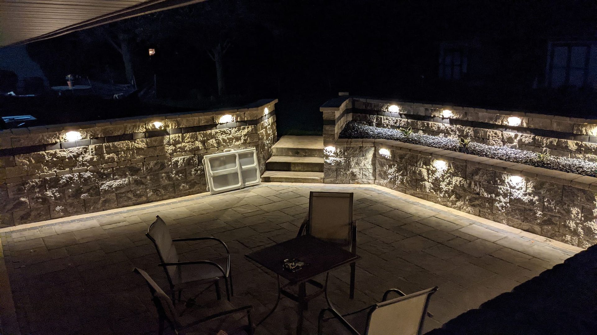 A patio with a table and chairs is lit up at night.