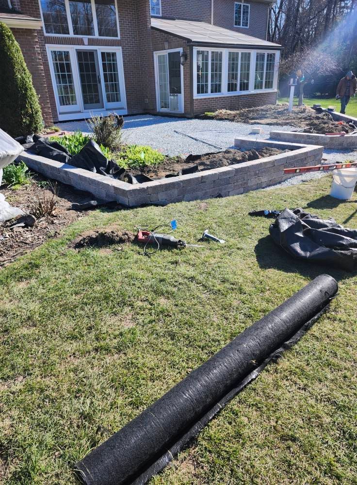 A roll of lawn covering is laying on the grass in front of a house.