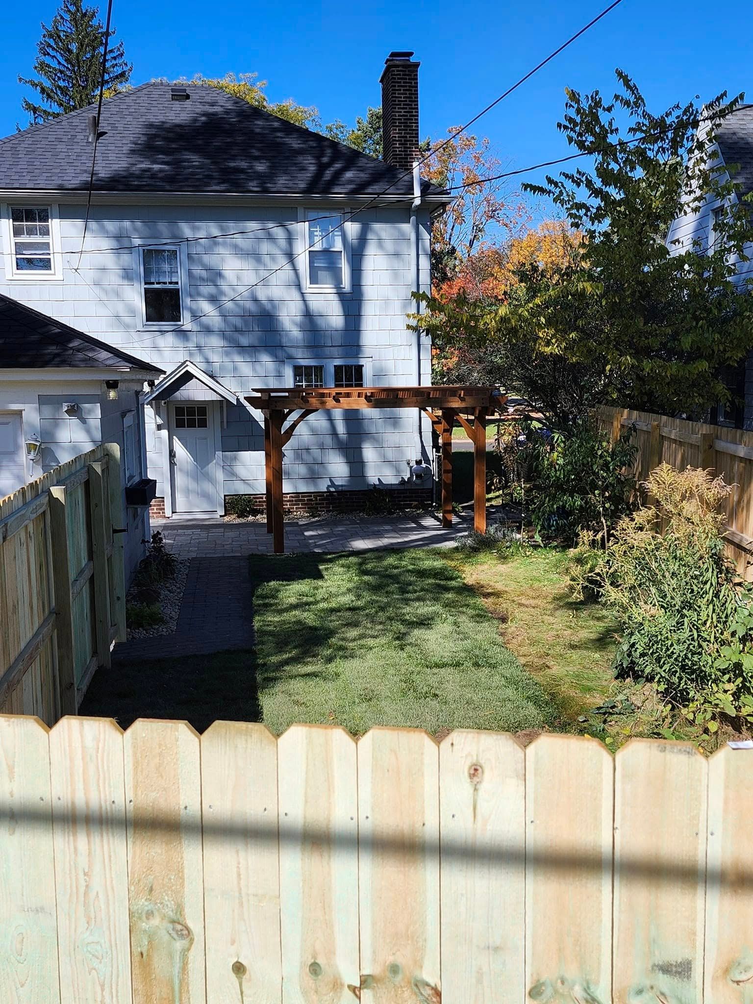 A backyard with a wooden fence and a house in the background.