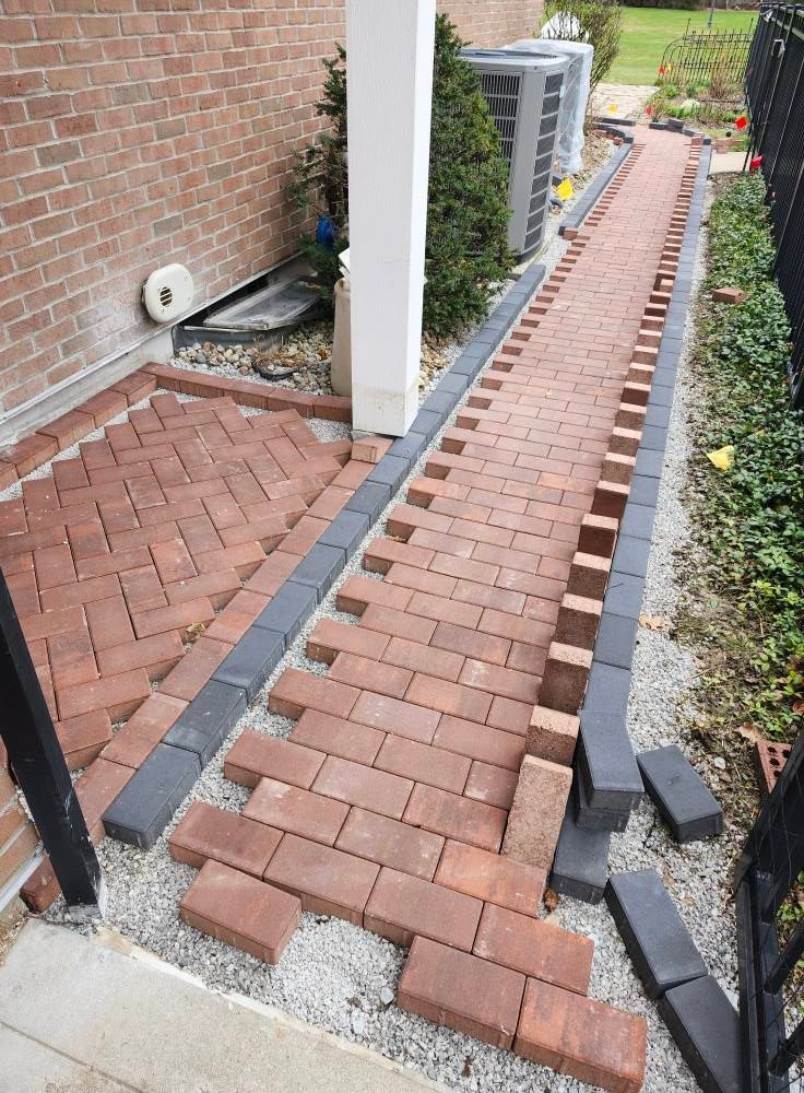 A brick walkway is being built in front of a brick house.