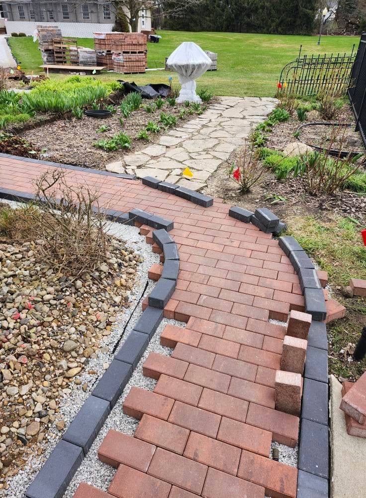 A brick walkway is being built in a garden