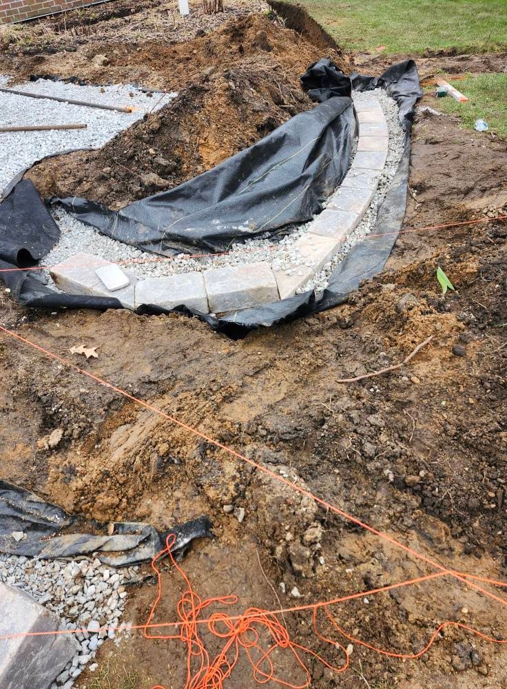 A large pile of dirt is being covered with a black tarp.