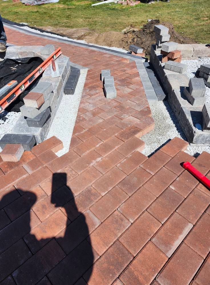 A person is taking a picture of a brick walkway being built.