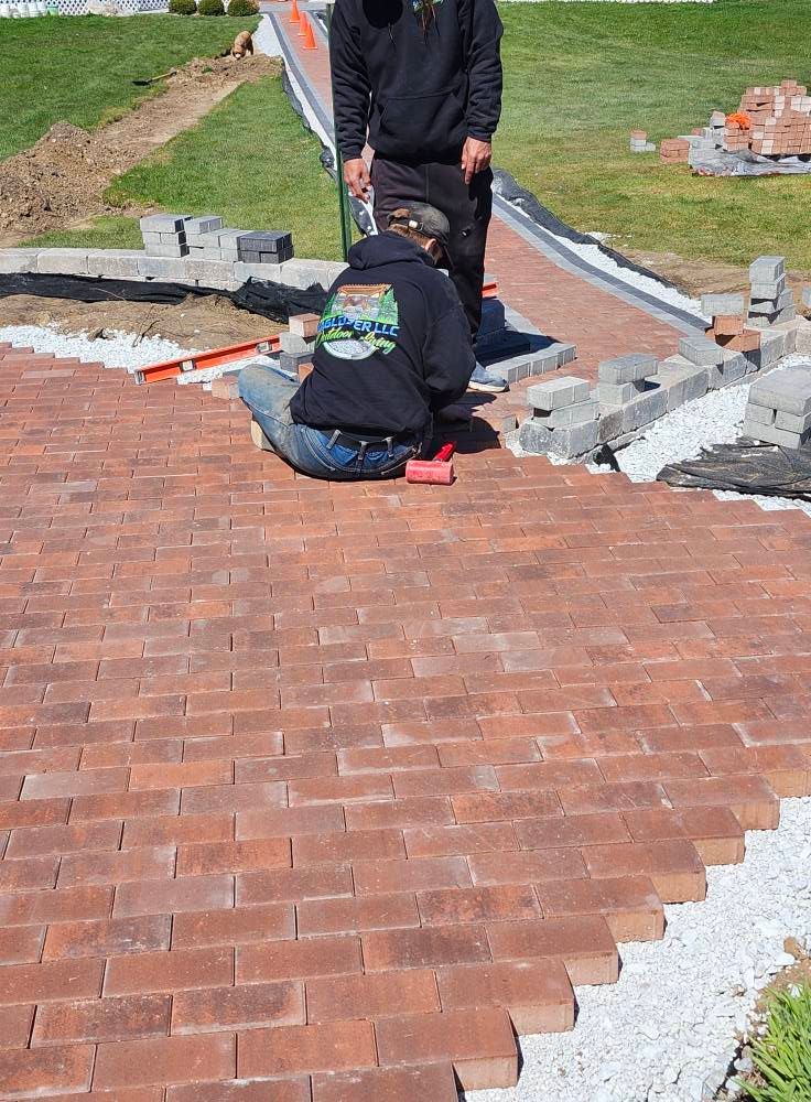 Two men are working on a brick walkway.