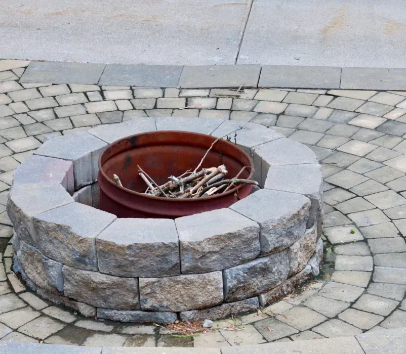 A fire pit is surrounded by bricks on a patio.