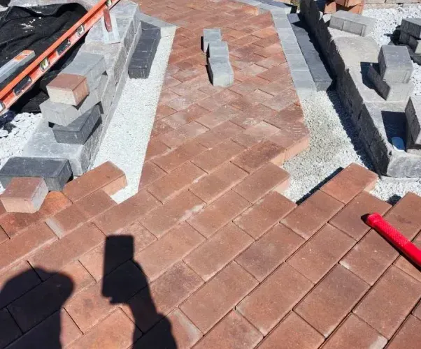 A person is taking a picture of a brick walkway being built.