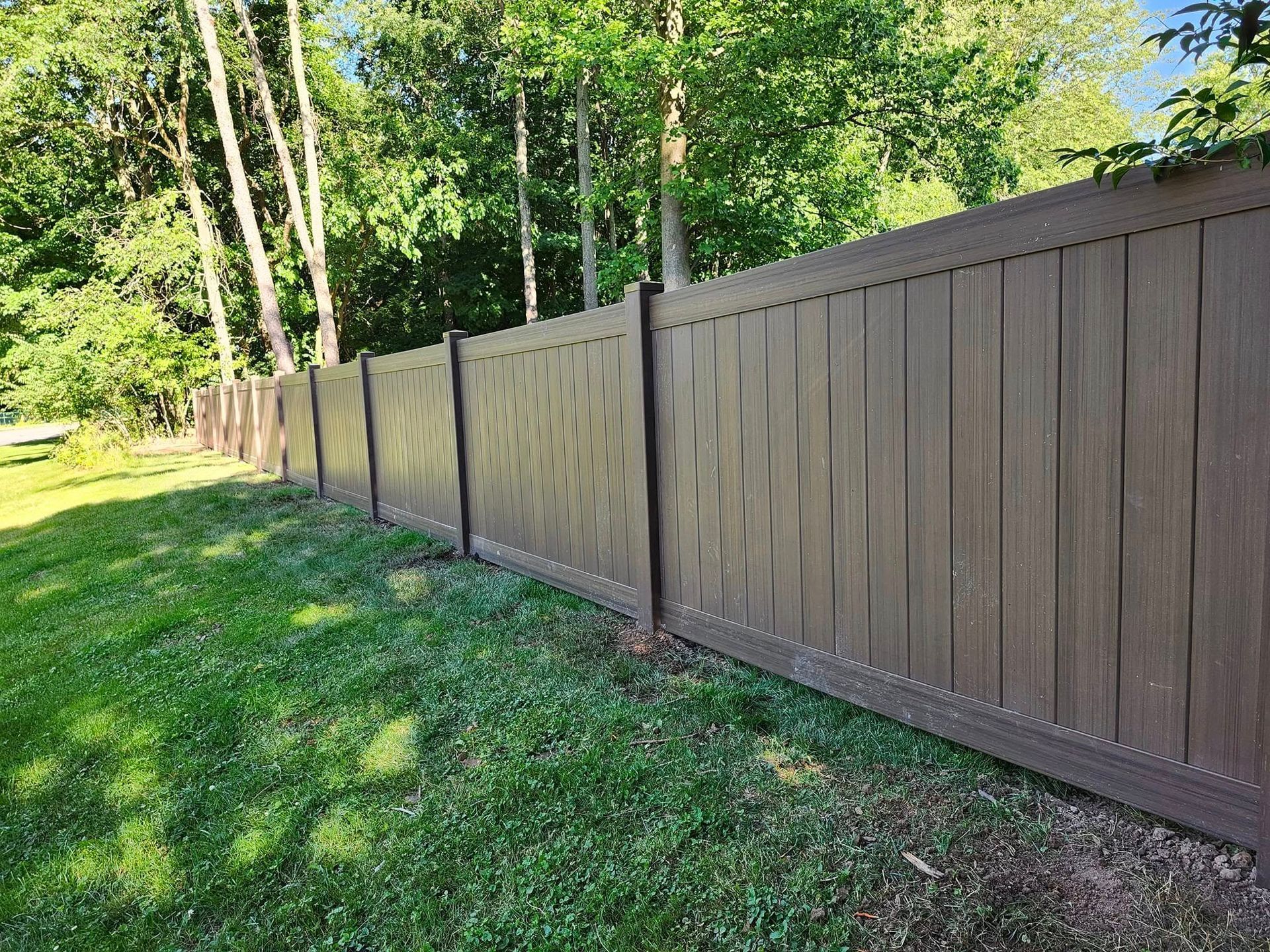 A brown wooden fence surrounds a lush green yard.