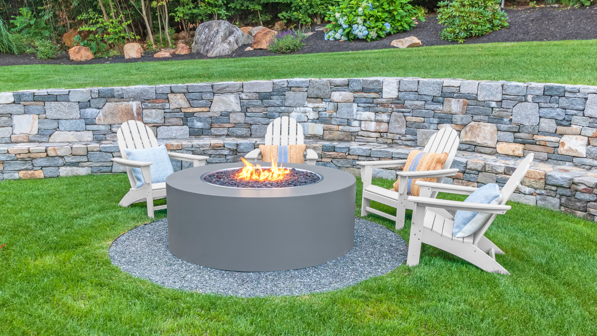 A fire pit with three chairs around it in a backyard.