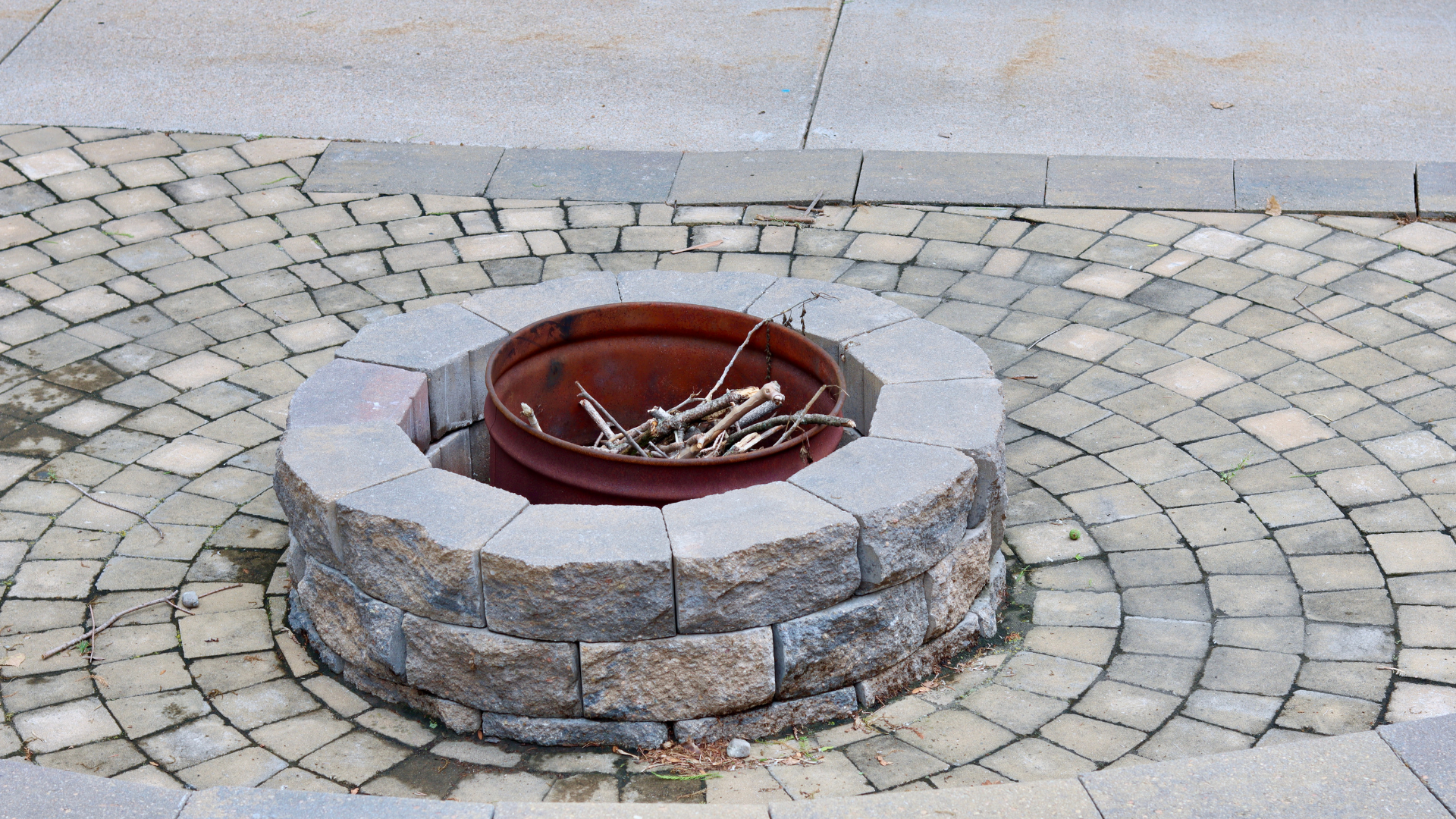 A fire pit is surrounded by bricks on a patio.