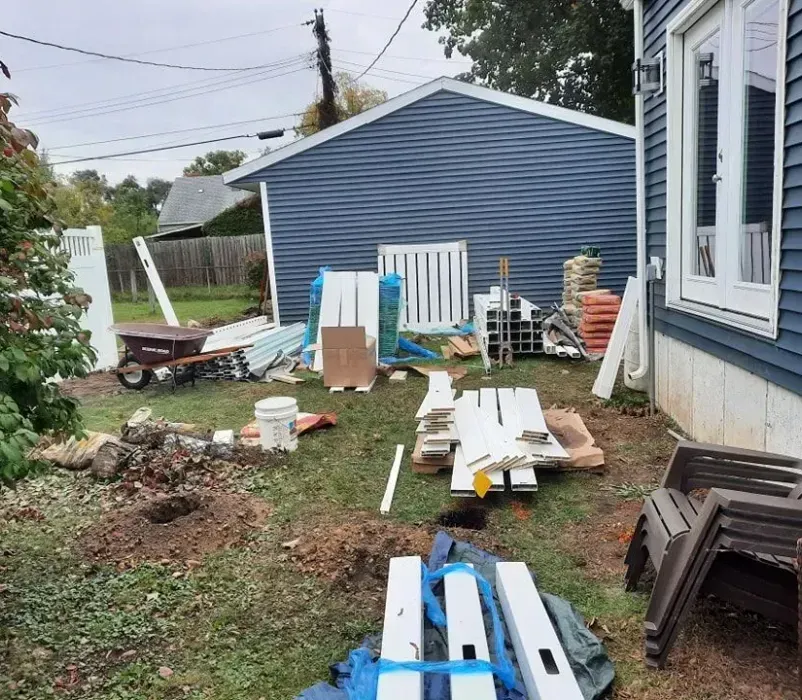 A backyard filled with lots of junk and a house in the background.