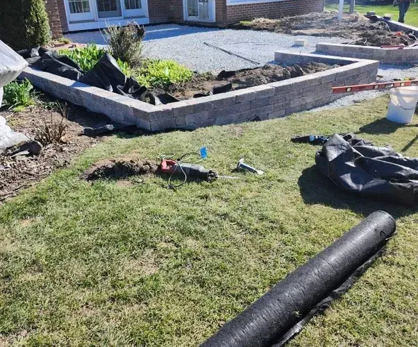 A roll of lawn covering is laying on the grass in front of a house.