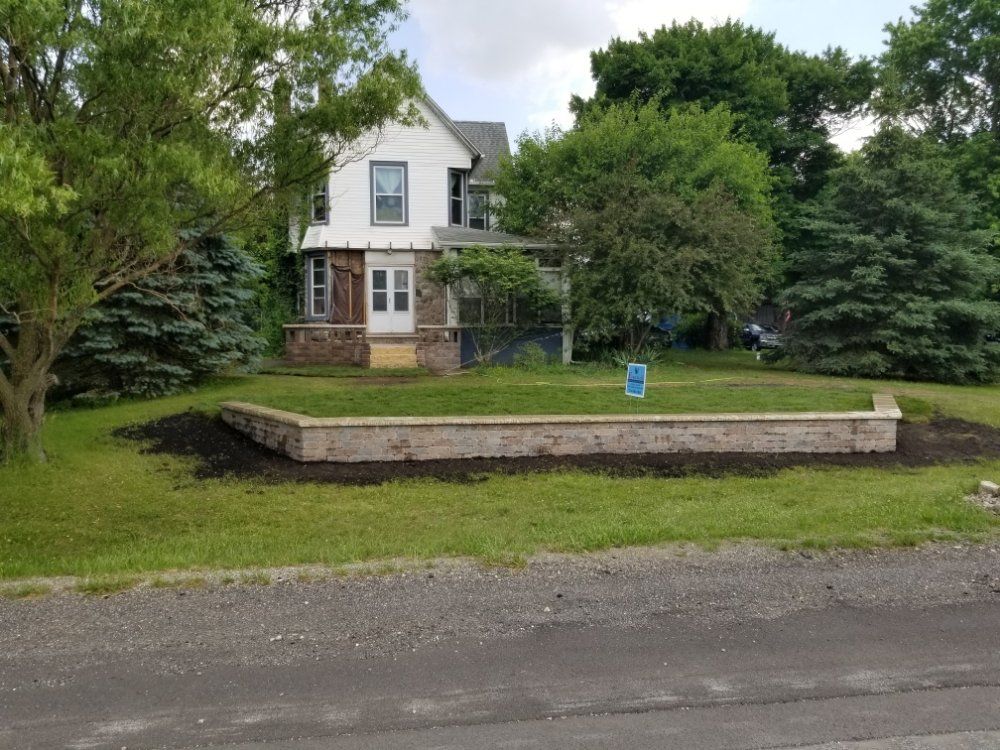 A white house with a brick wall in front of it.