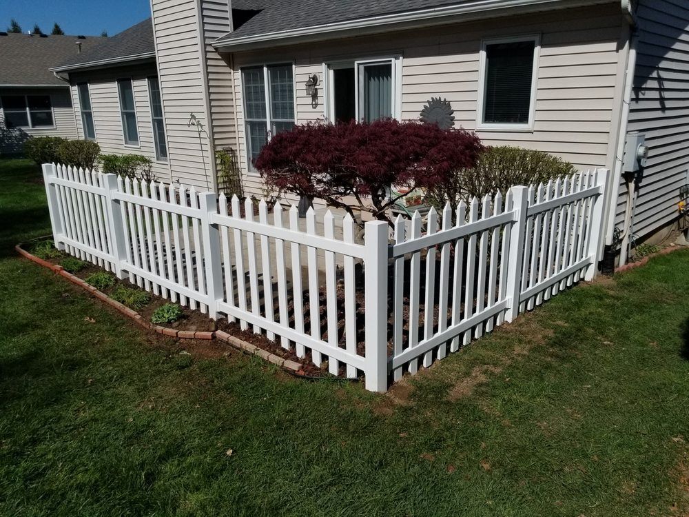 A white picket fence is in front of a house.