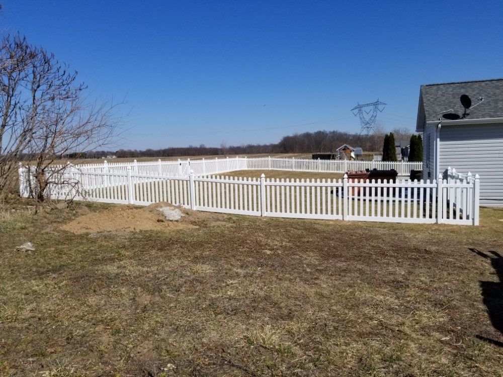 A white picket fence surrounds a yard in front of a house.
