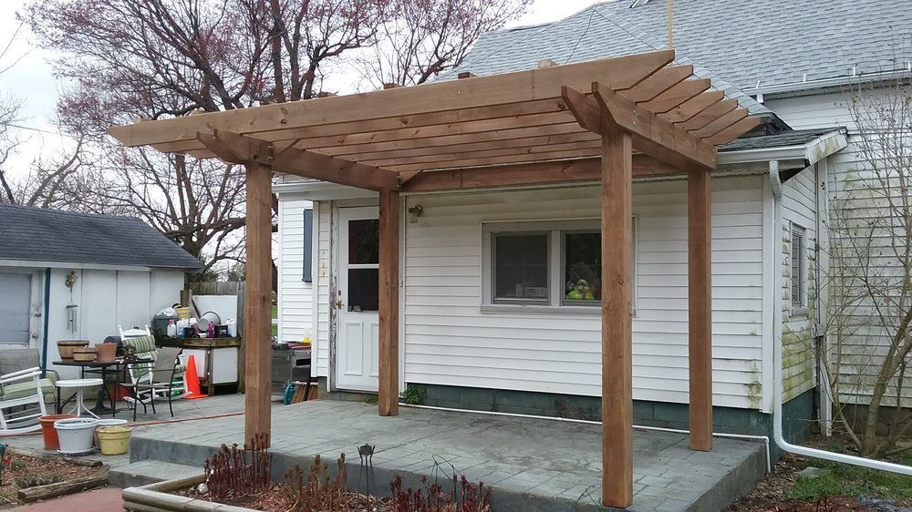 A white house with a wooden pergola in front of it