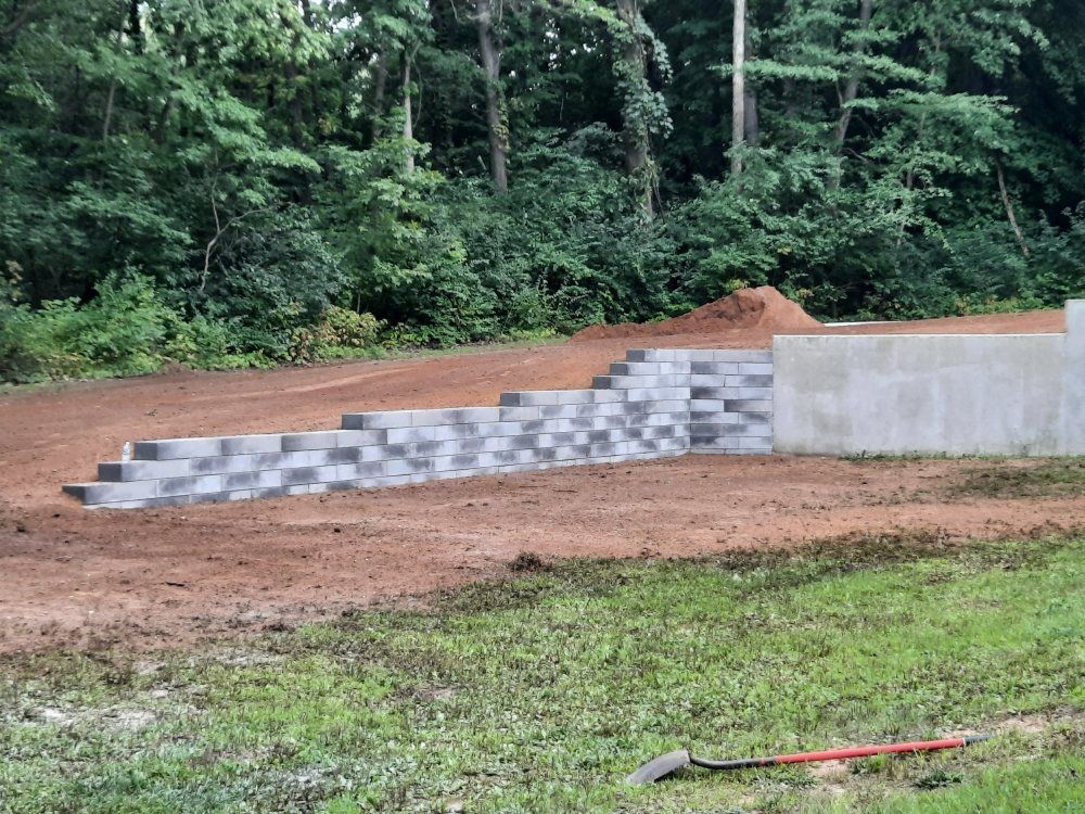 A brick wall is being built in the middle of a dirt field.