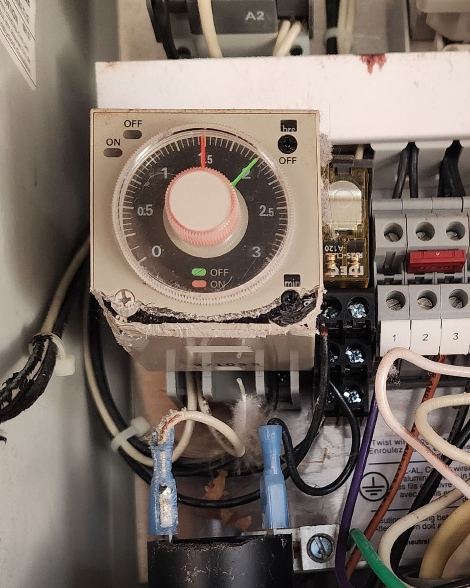 Electrical control panel with a rotary timer switch and wiring inside a cabinet.