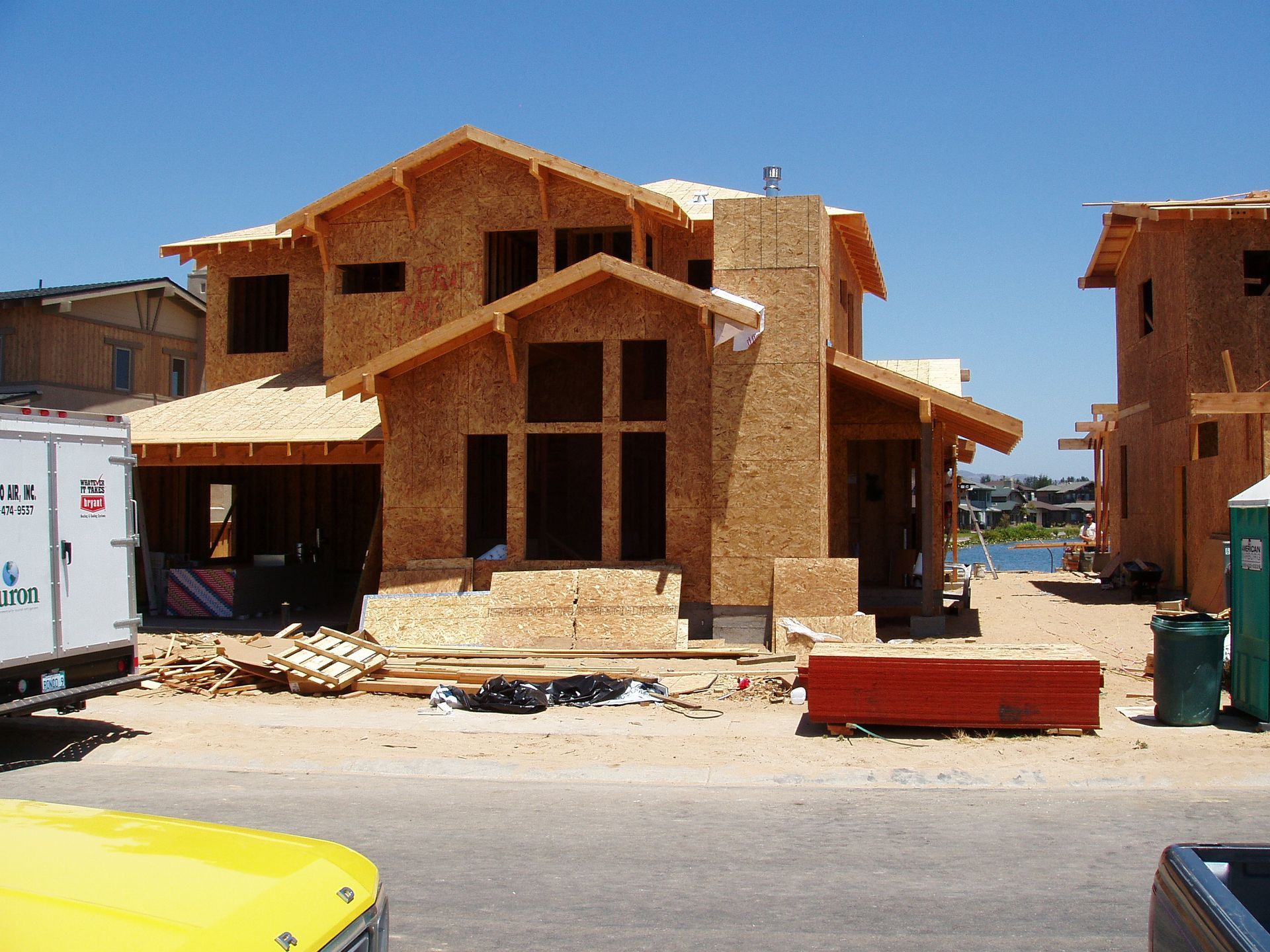 House under construction with exposed wood frame, on a sunny day.