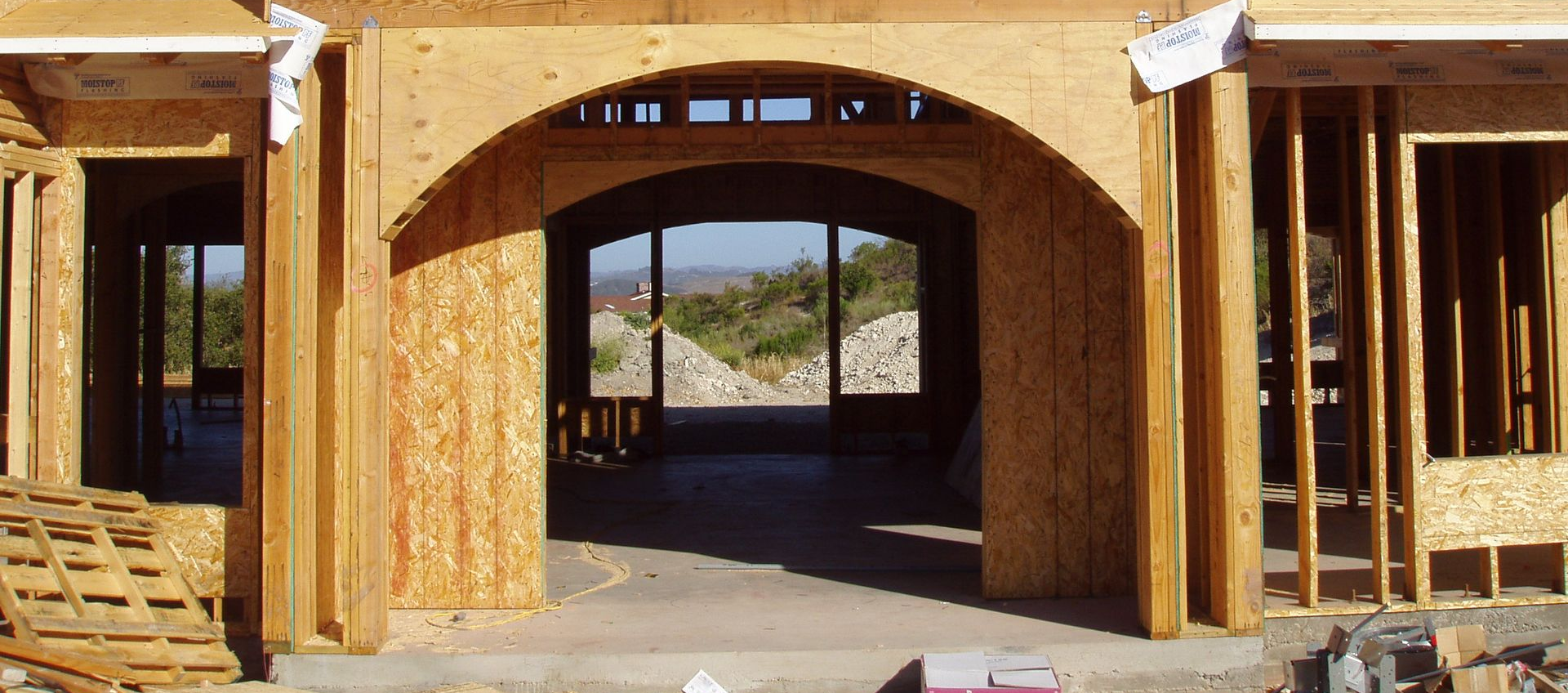 Construction site, wood frame archway and entryway. Views of hills through the opening.