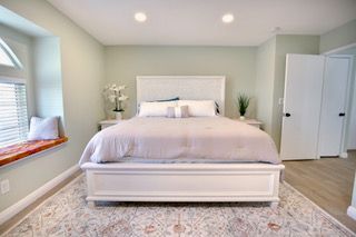 Bedroom with a white bed, light green walls, and a window seat.