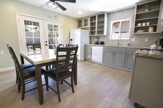 A well-lit kitchen with a dining table, cabinets, appliances, and doors leading to the outside.