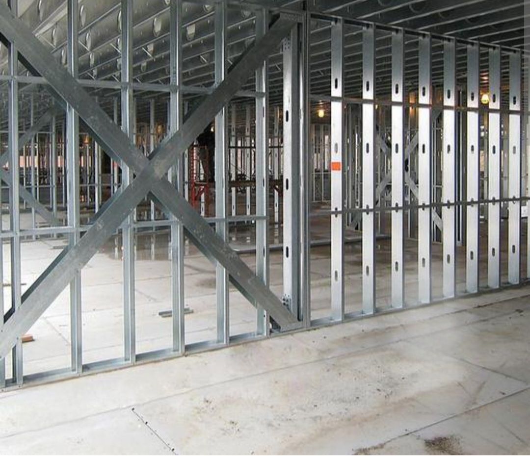 Steel framing of an interior wall with an X-brace for stability; on a concrete floor.
