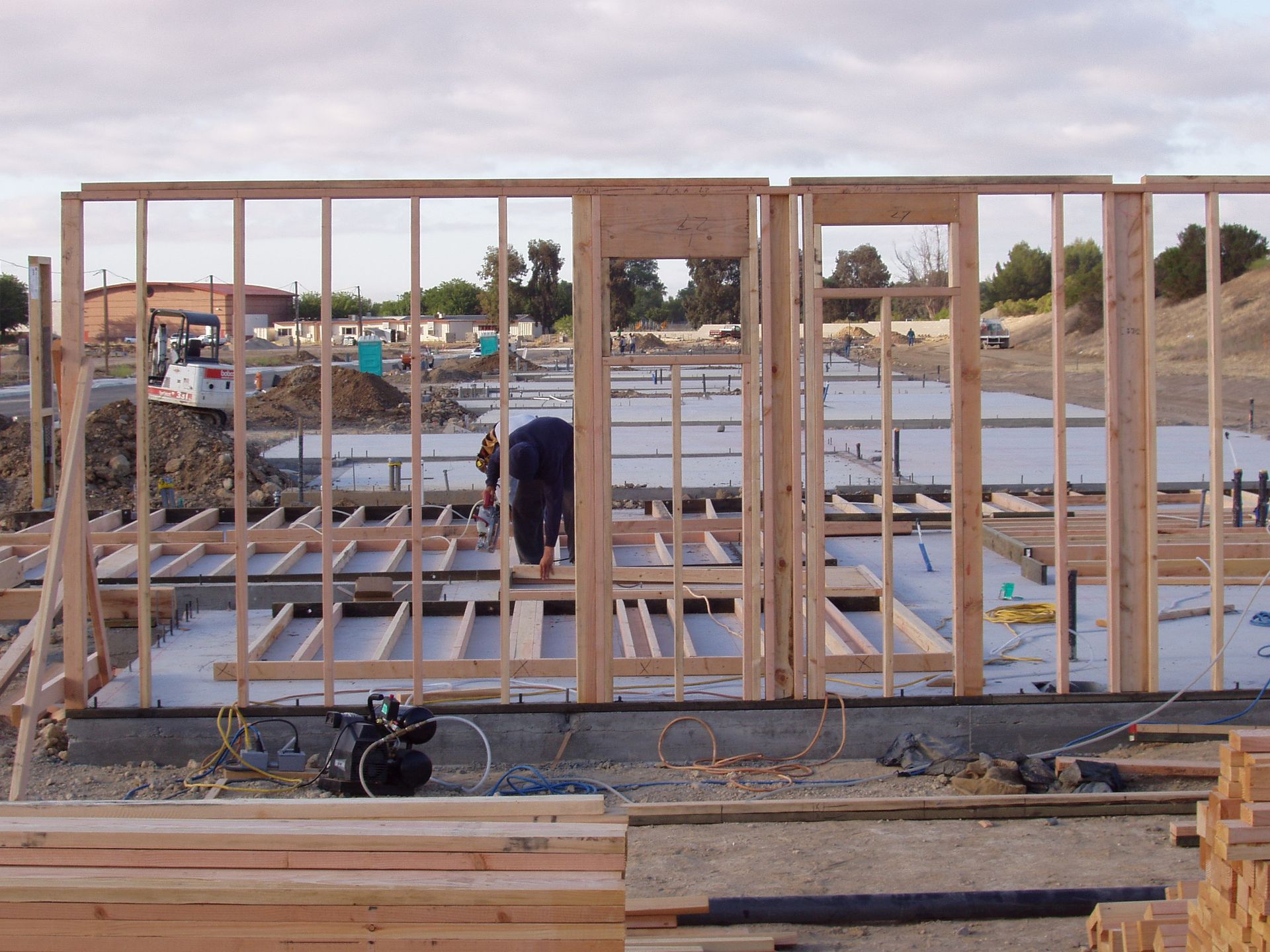 Construction site with wooden framing for a building, worker, and foundation.
