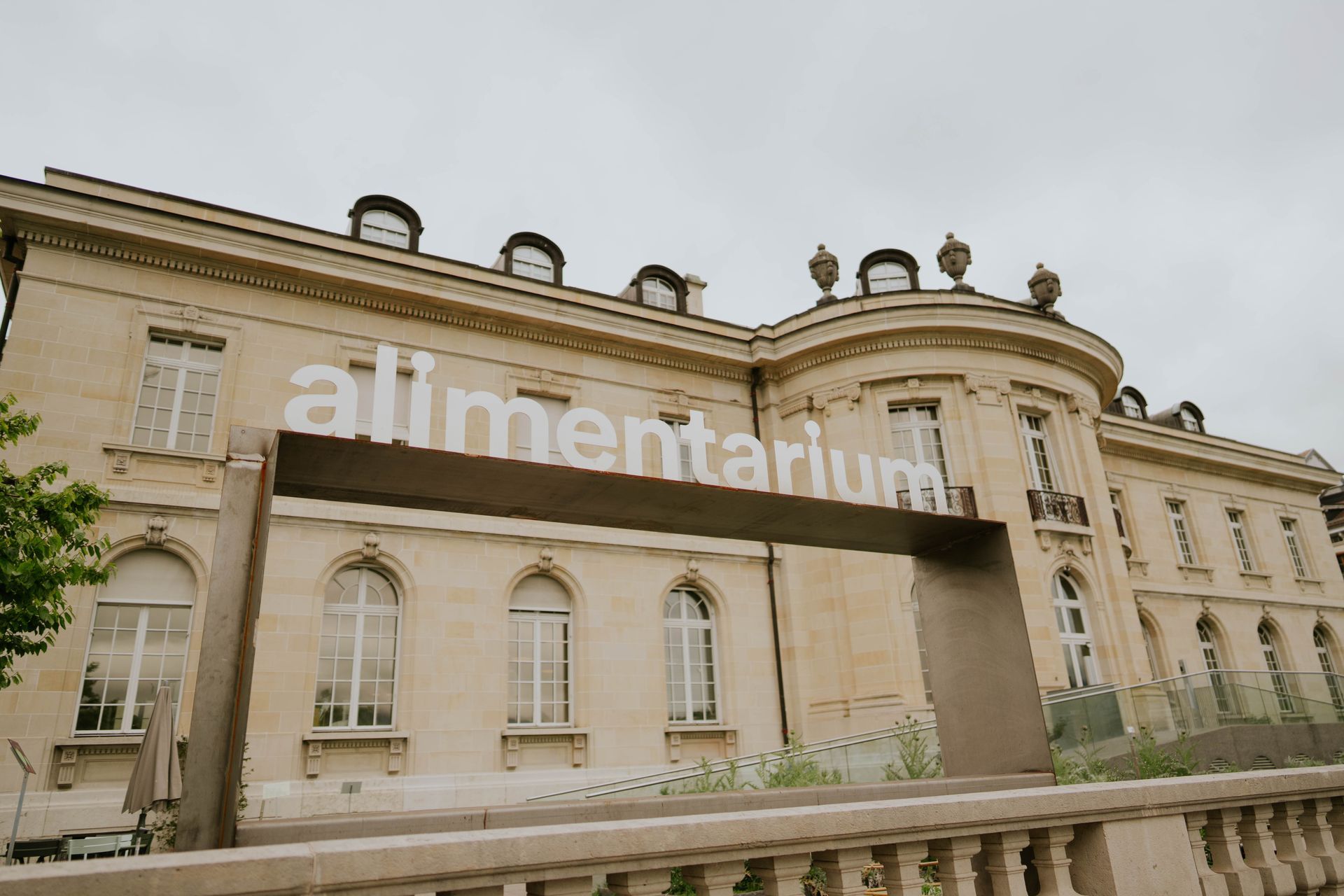 Exterior view of the Alimentarium, a museum in a light-colored building. The museum's name is in large white letters.