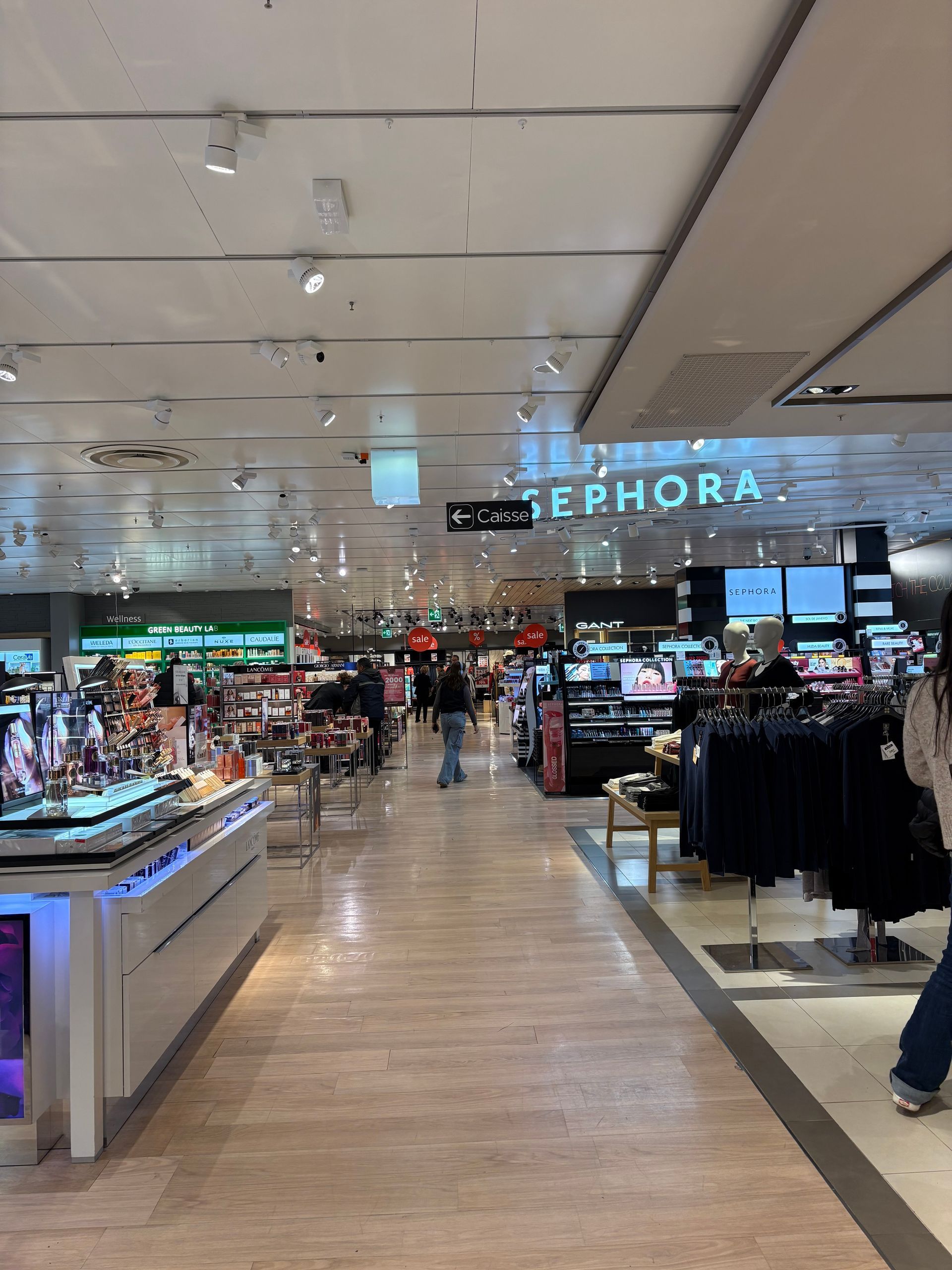 Interior view of a Sephora cosmetics store with aisles of displays and shoppers browsing.