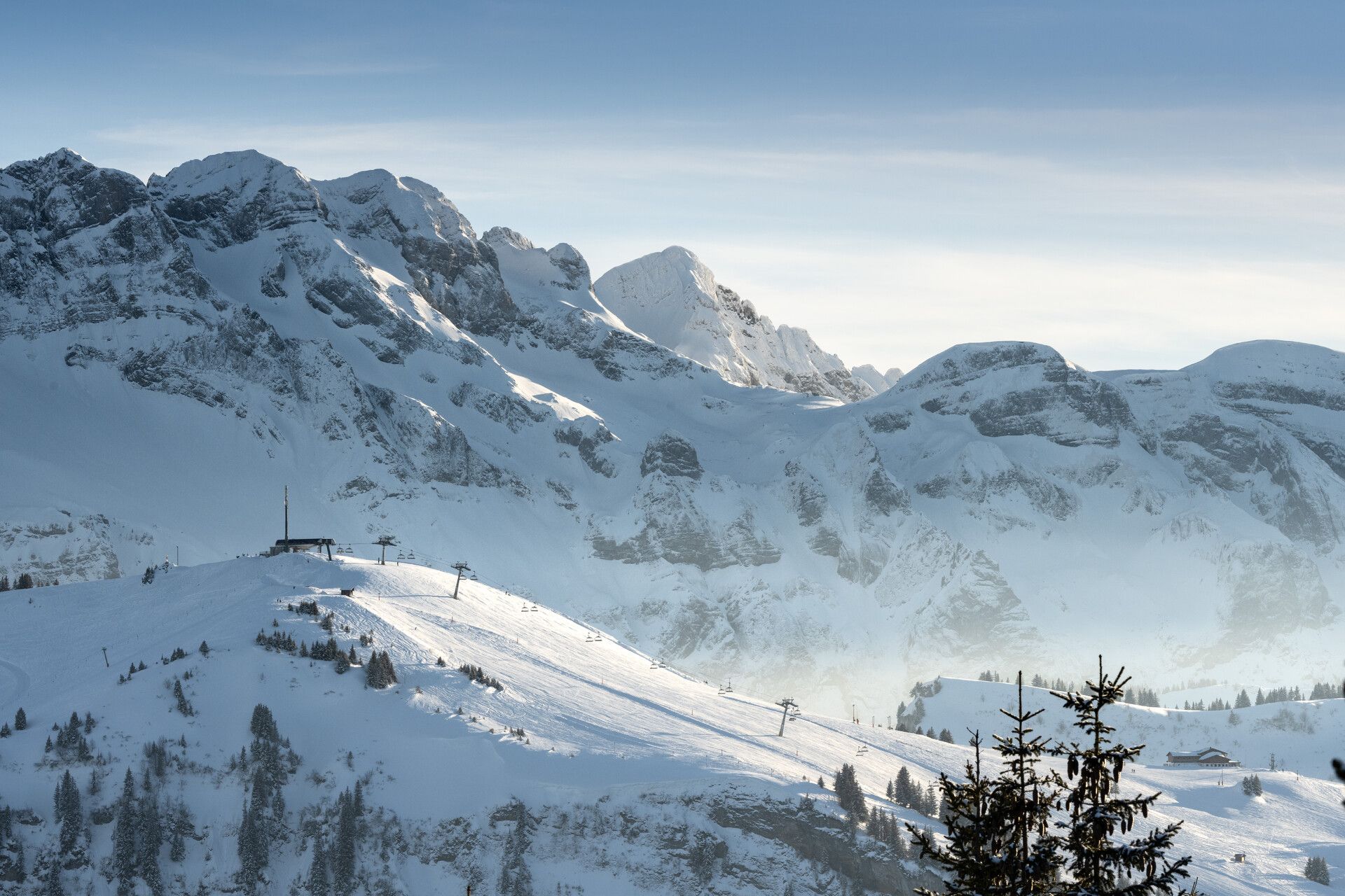 Snowy mountain range with ski lifts and clear blue sky.