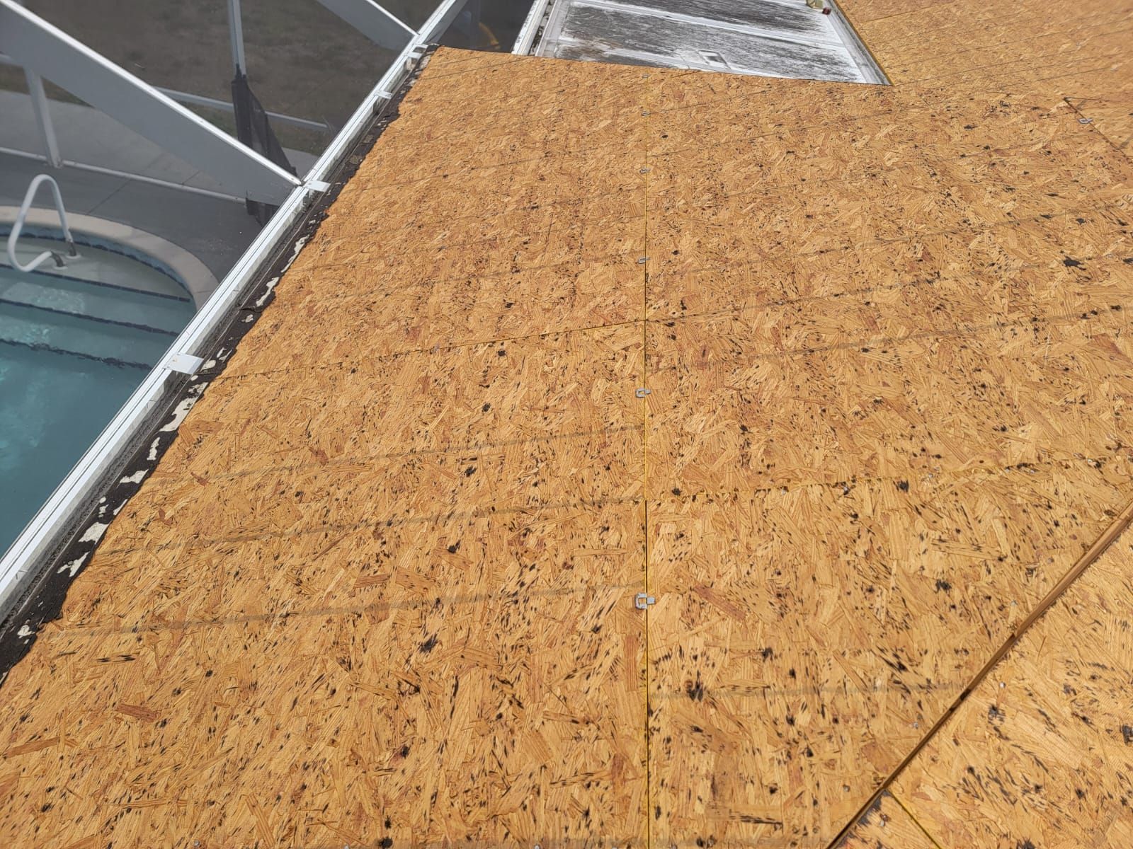 A close up of a roof with a pool in the background.